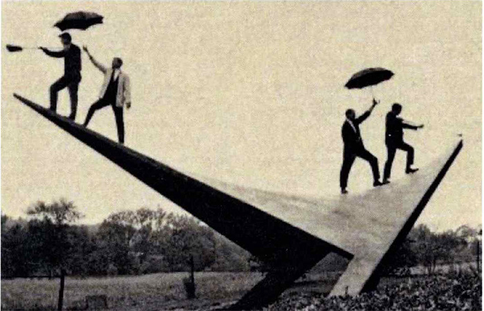 Students and faculty standing on the structure carrying umbrellas