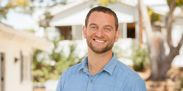 Man with short brown hair smiling wearing a light blue shirt