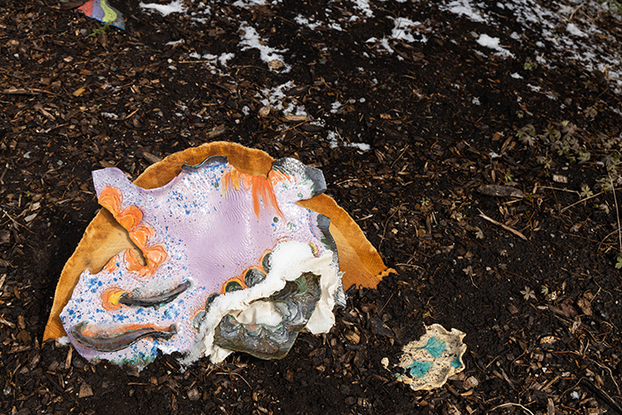 up close image of a purple and yellow ceramic sculpture in a bed of soil