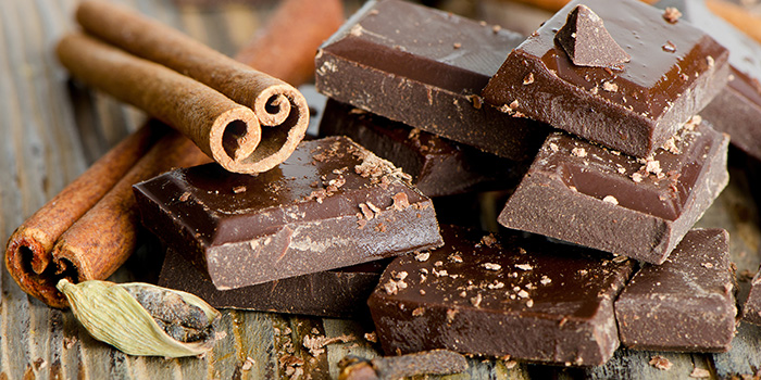 Broken chocolate bar and spices on wooden table. Selective focus