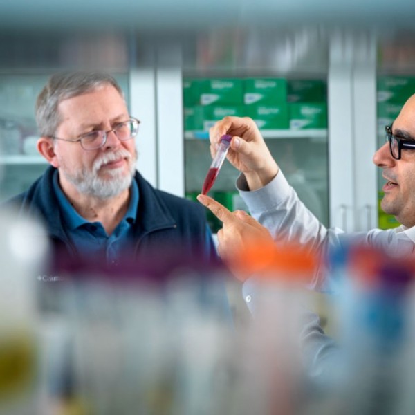 Two researchers examine a vial of beet juice