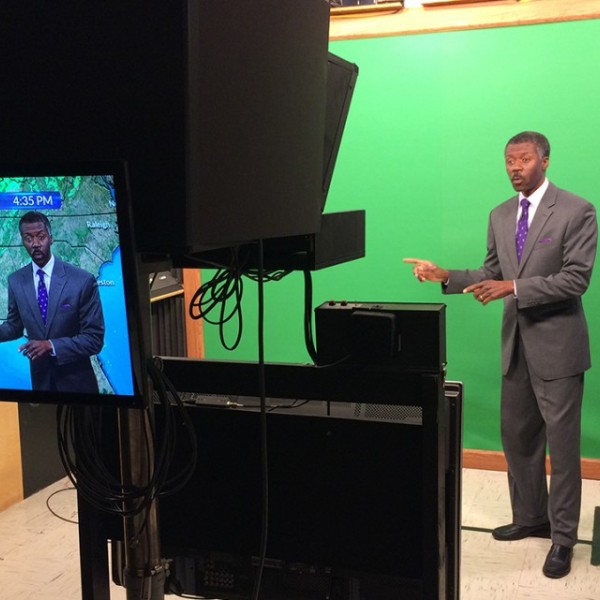 Alan Sealls stands in front of a green screen with a monitor in the foreground
