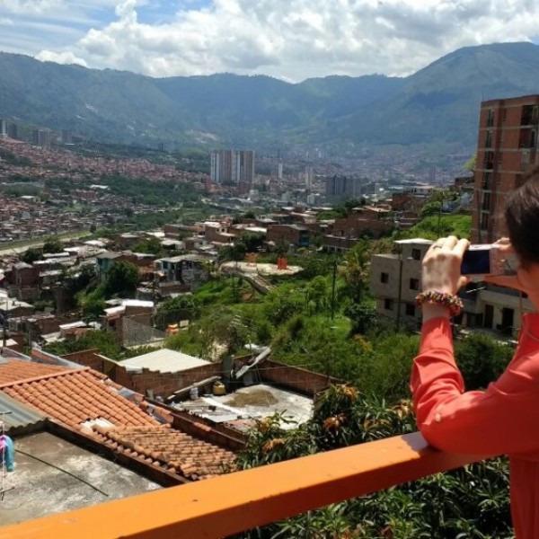 graduate student takes a photo of a city and mountains from a balcony