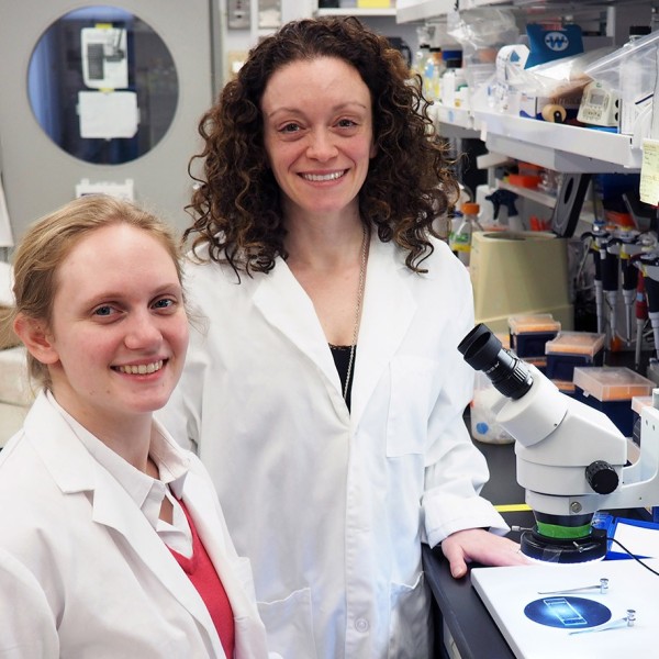 researcher and professor stand in a lab with a microscope