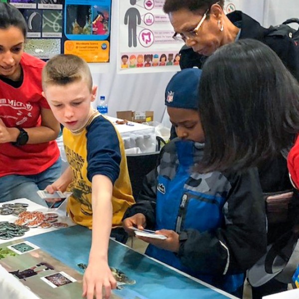 Cornell students interact with young students at table