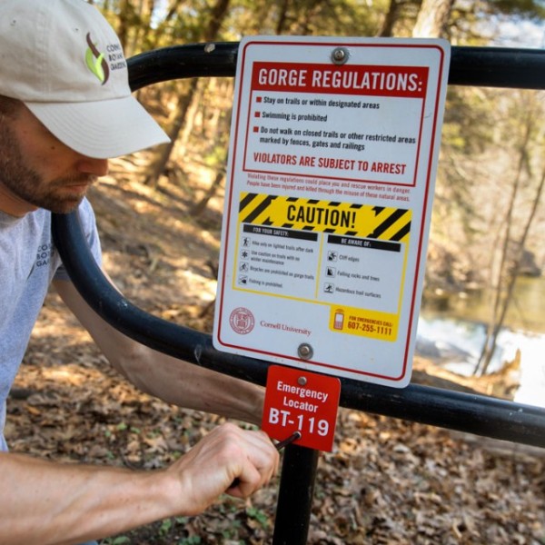 worker attaching a sign to a gate