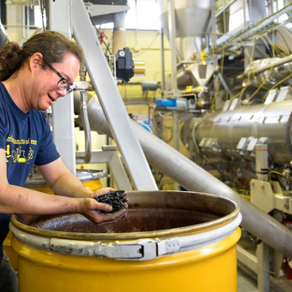 Man stands over bucket of biochar