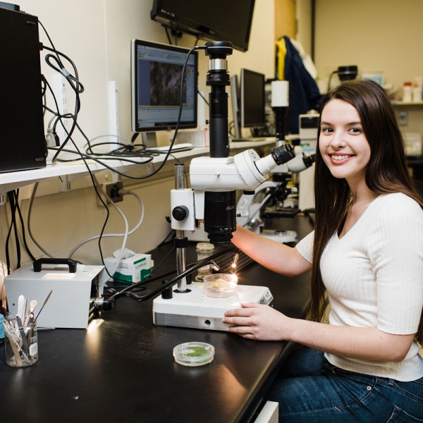 Breanne Kisselstein sits with a microscope