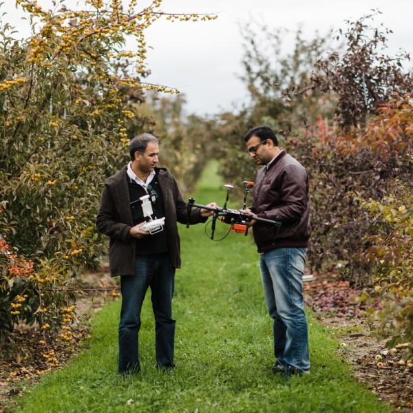 2 men in crop filed with drone