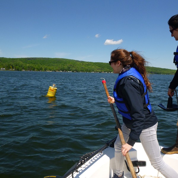 students on a boat ready to reach for a research bouy