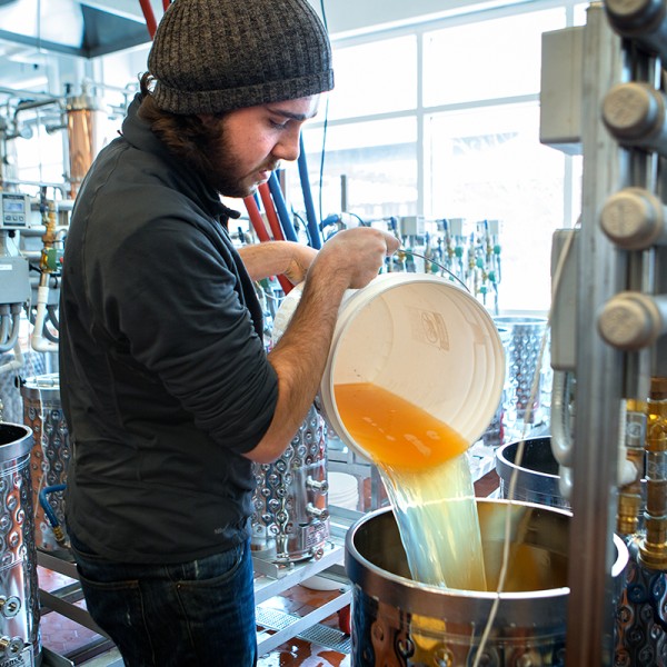 Collin Dillingham pouring apple juice into a fermentation tank