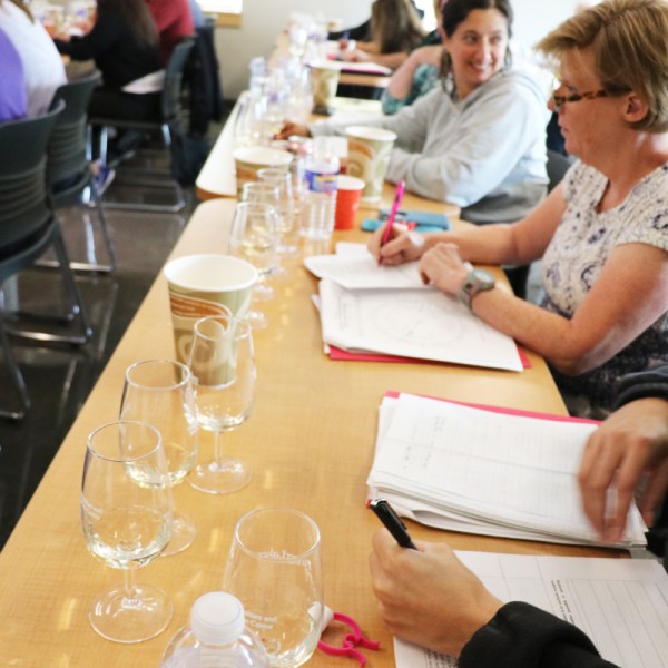 People at a table with wine glasses and reading information in front of them