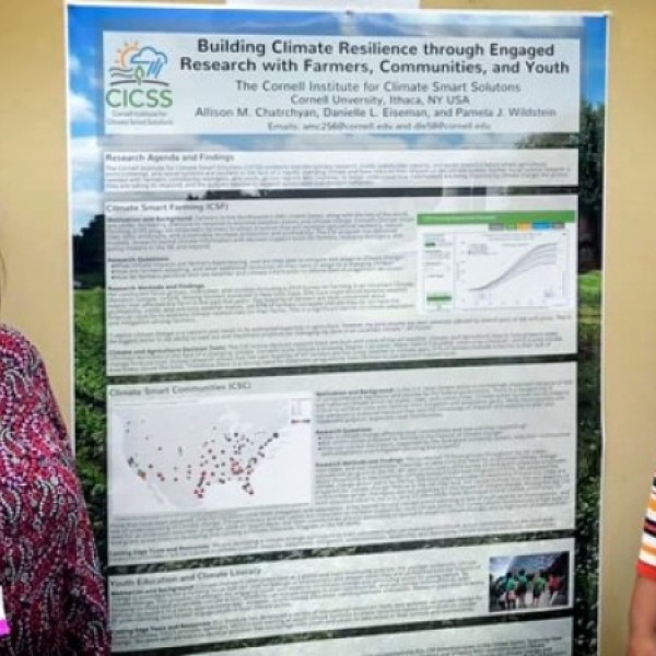 Two women stand on either side of a poster detailing climate change research