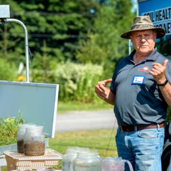 A man stands outside and conducts a demonstration using plants