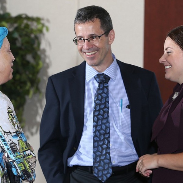 Three faculty members stand and talk to each other