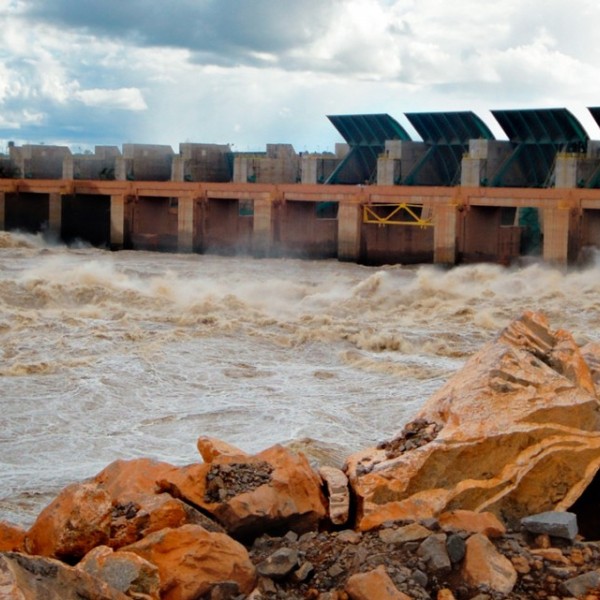 a large long cement structure in the middle of a body of water with waves crashing around it