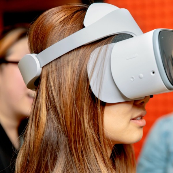 A female student wearing virtual reality goggles while other students look on
