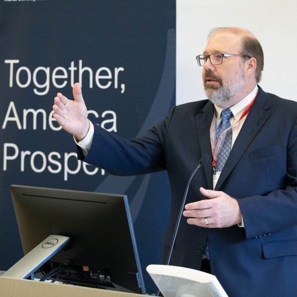 A white male standing at a podium speaking and gesturing