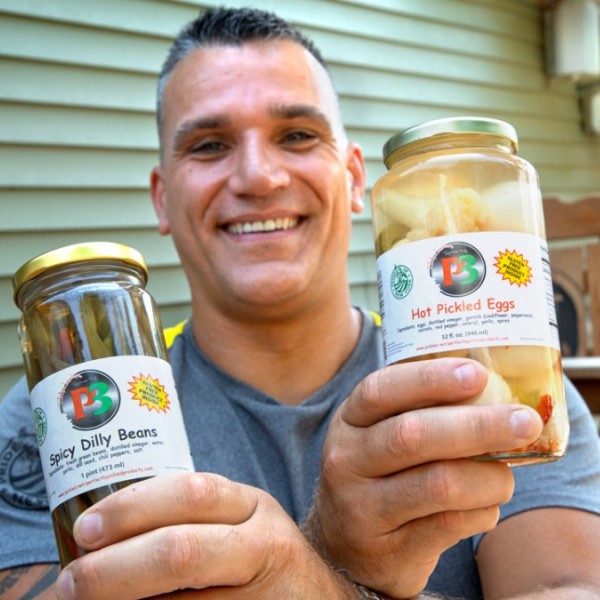 A man holding two jars of pickles 