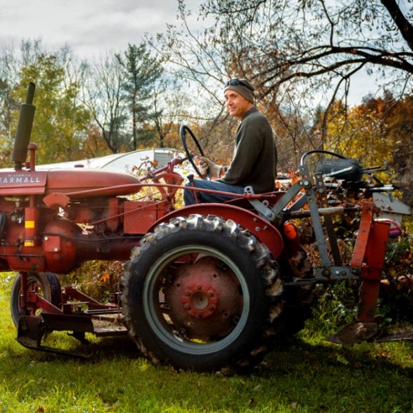 A man sitting on a red tractor outside 