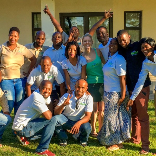 A group of men and women stand outside a building and make celebratory gestures