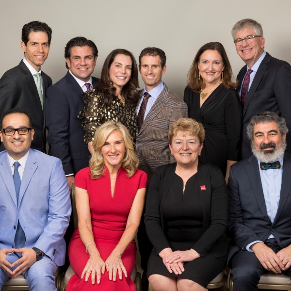 Two women and two men sit in the front row, while two women and four men stand and smile in the background of a posed picture