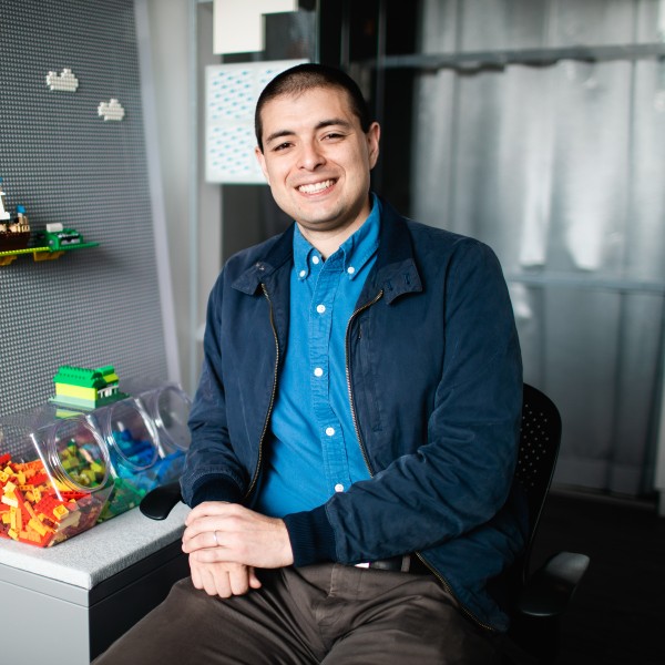 A man with short brown hair sitting in a chair in an office 