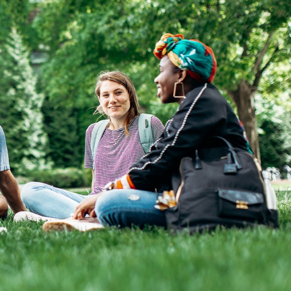 Four students sit in the lawn and talk 