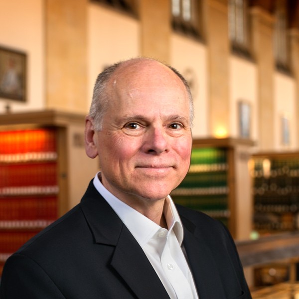 Max Pfeffer stands in a library to have his portrait taken