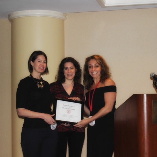 Three women stand holding a certificate