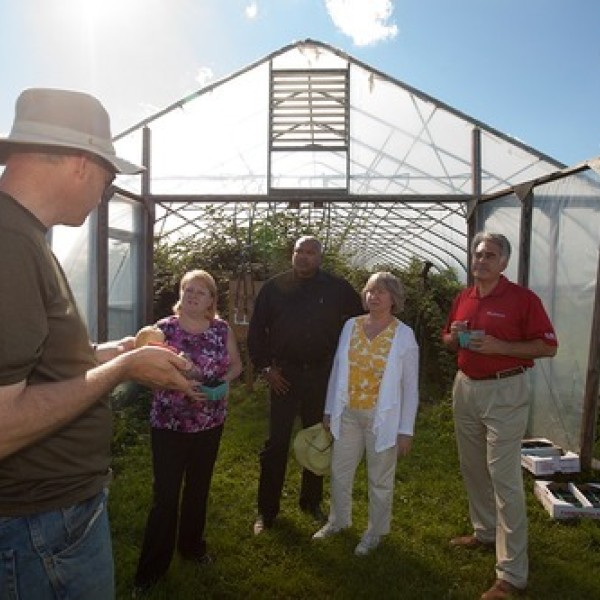 A group of people stand outside a greenhouse