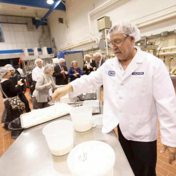 Many people stand in a dairy processing plant