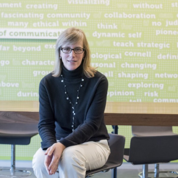 A woman sits on a chair in the Cornell department of communication