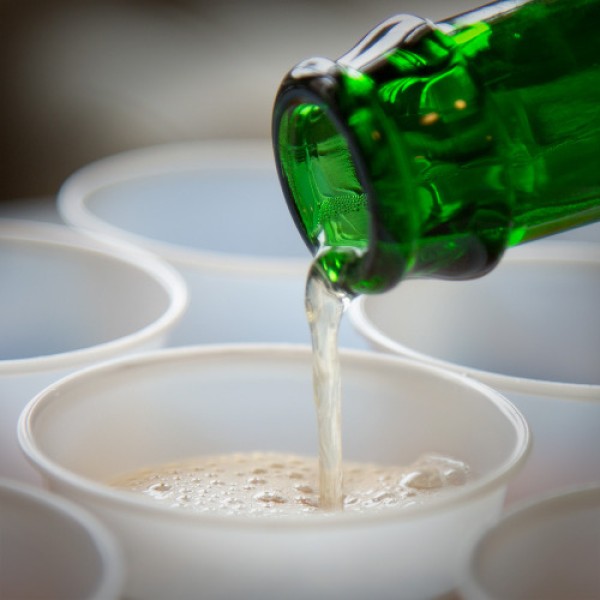 A closeup image of beer being poured out of a green beer bottle