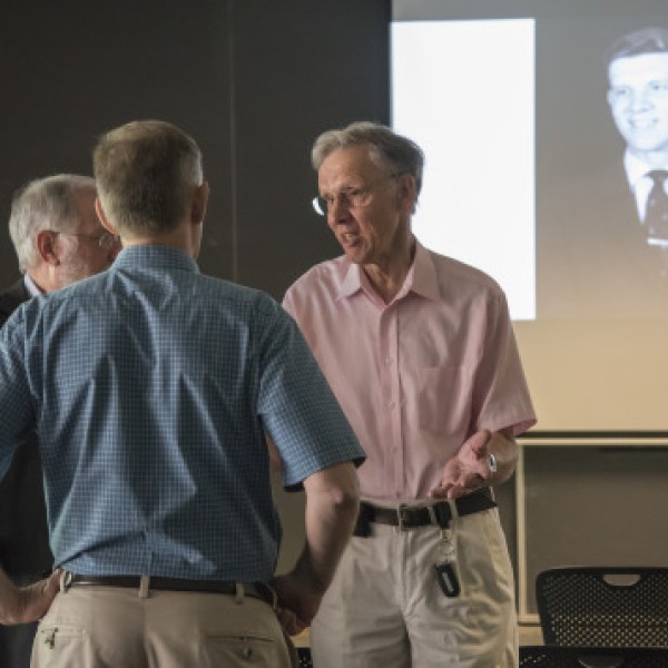 Three men standing together and speaking