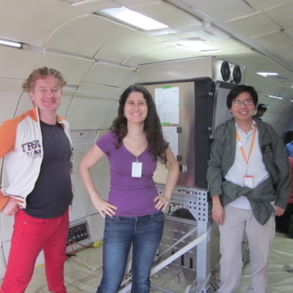 Three people stand inside a space simulator