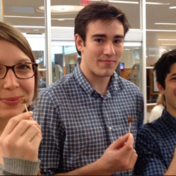 A woman and two men stand holding mealworm-based meat on toothpicks