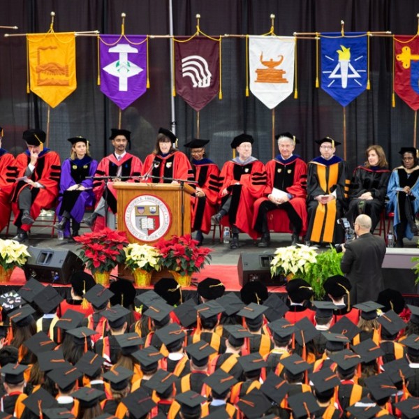 A graduation ceremony with the faculty sitting on stage in red robes