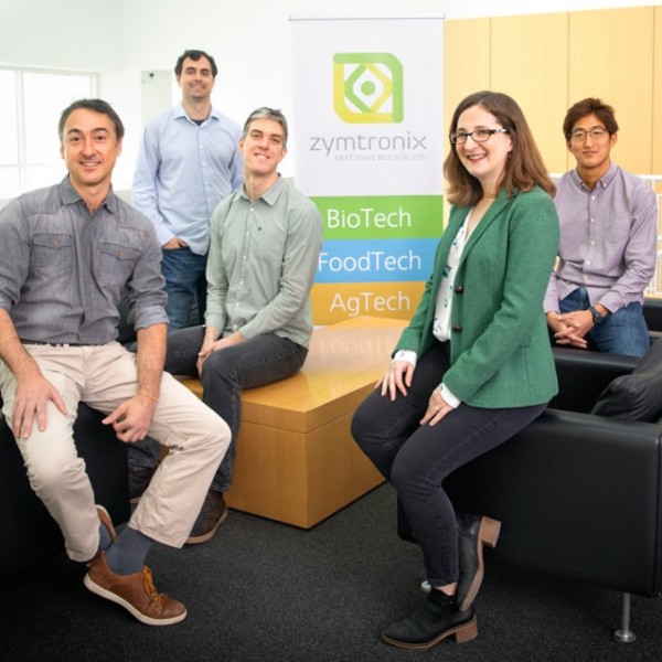 one female and four males standing in an open seating area in a building 