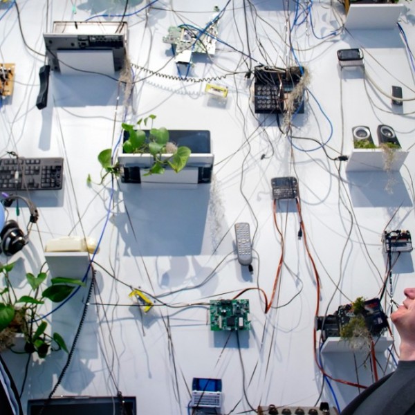 Two men looking up at a large white wall with technology and plants on it