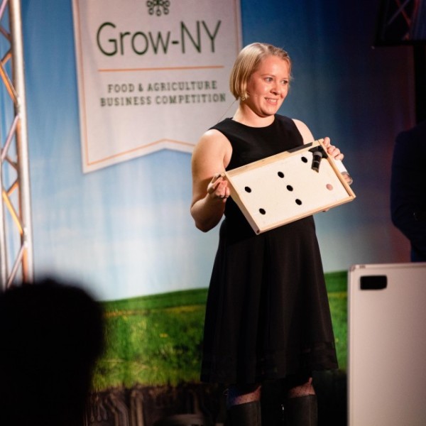Woman smiles on stage as she presents a project