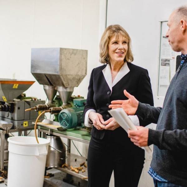 A woman and a man speak with each other while standing in a lab