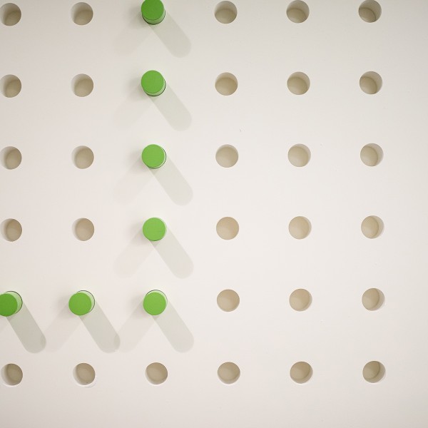 A white wall with green pegs in it