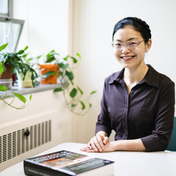 A woman sits at a table and smiles