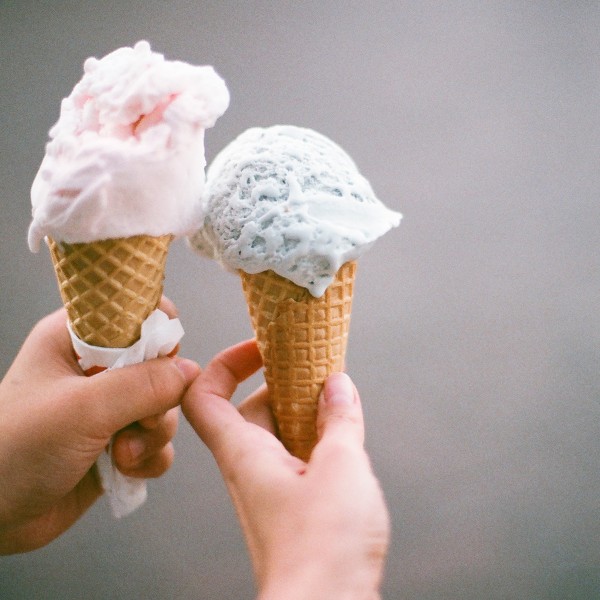 Two hands holding ice cream cones. 