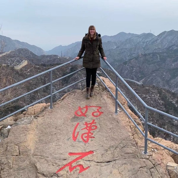 a college-aged woman stands by a railing on the Great Wall of China