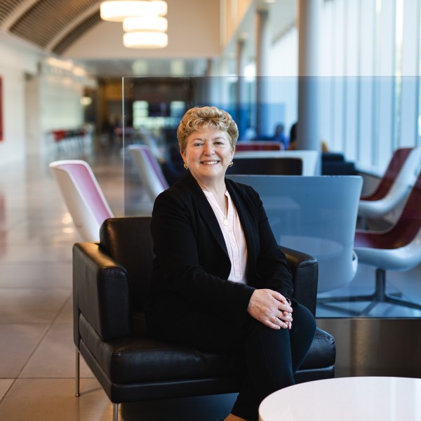 a woman sits in an armchair in a sunlit corridor