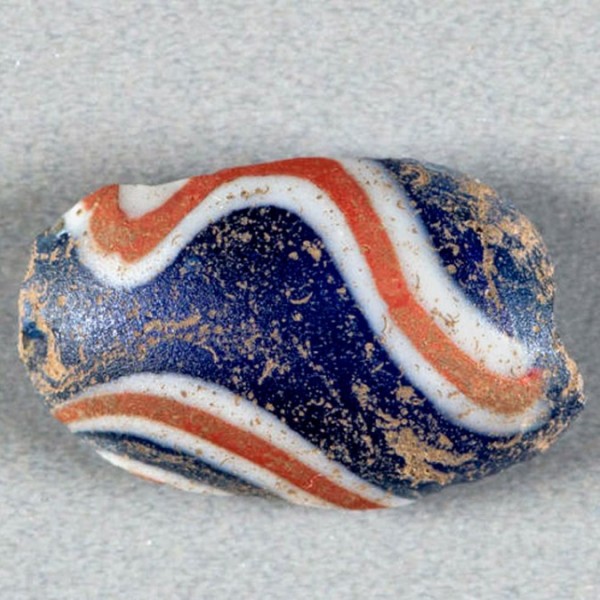 A blue bead with white and orange curving lines