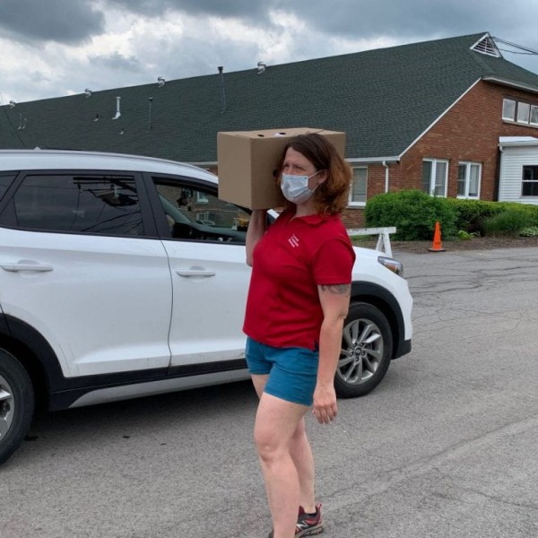 CCE staff member carries food box on their shoulder