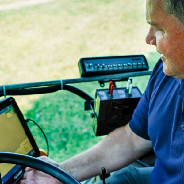 Terry Bates looks at computer while on his tractor
